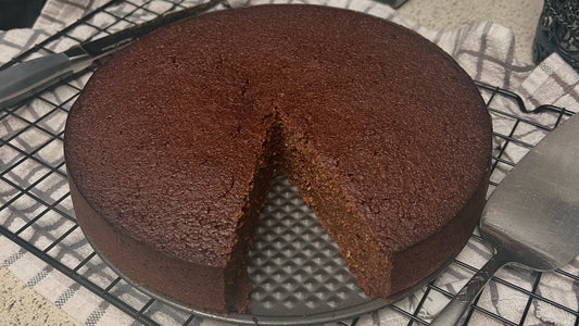 Caribbean Black Cake with a slice cut out and kitchen utensils in the background